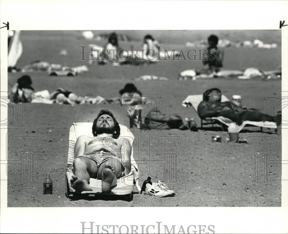 1986 Press Photo Joe Brown sun bathes on the beach of Mentor Headland Park - Historic Images