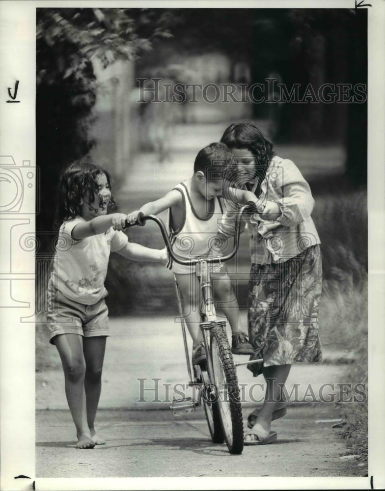 1982 Press Photo Arlene Cuevas and Oneida Cedoeno teach Elmer to ride a bike. - Historic Images