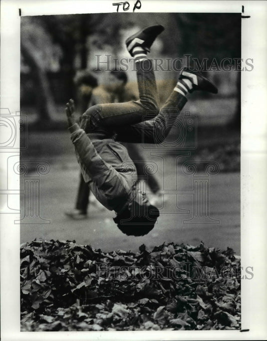 1987 Press Photo Mauricio Rojas flips in leaves at Carneige West Branch Lib Ohio - Historic Images