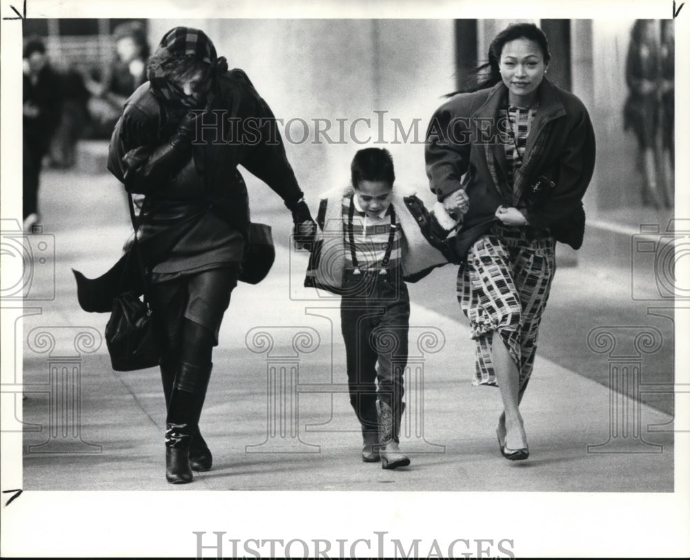 1988 Press Photo Pedestrians struggle against the wind as they walk on sidewalk - Historic Images