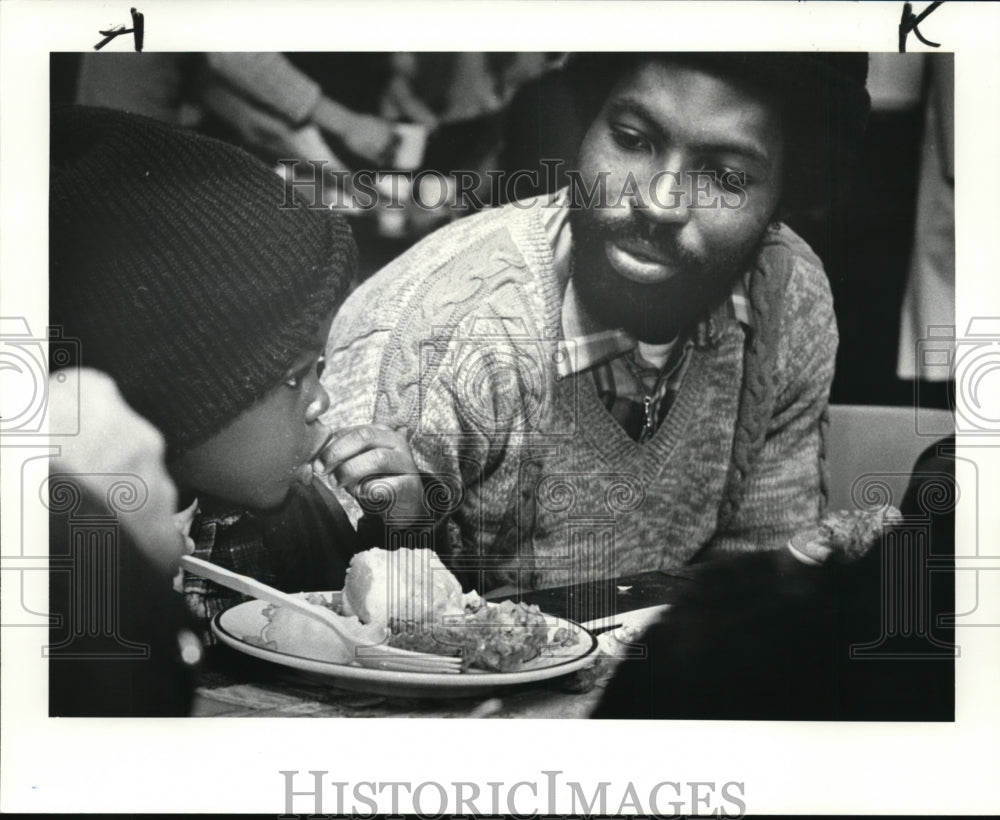 1983 Press Photo Sly Sanders and 4 Year Old Son Enjoy Christmas Dinner - Historic Images