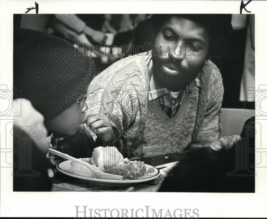 1983 Press Photo Sly Sanders and 4 Year Old Son Enjoy Christmas Dinner - Historic Images