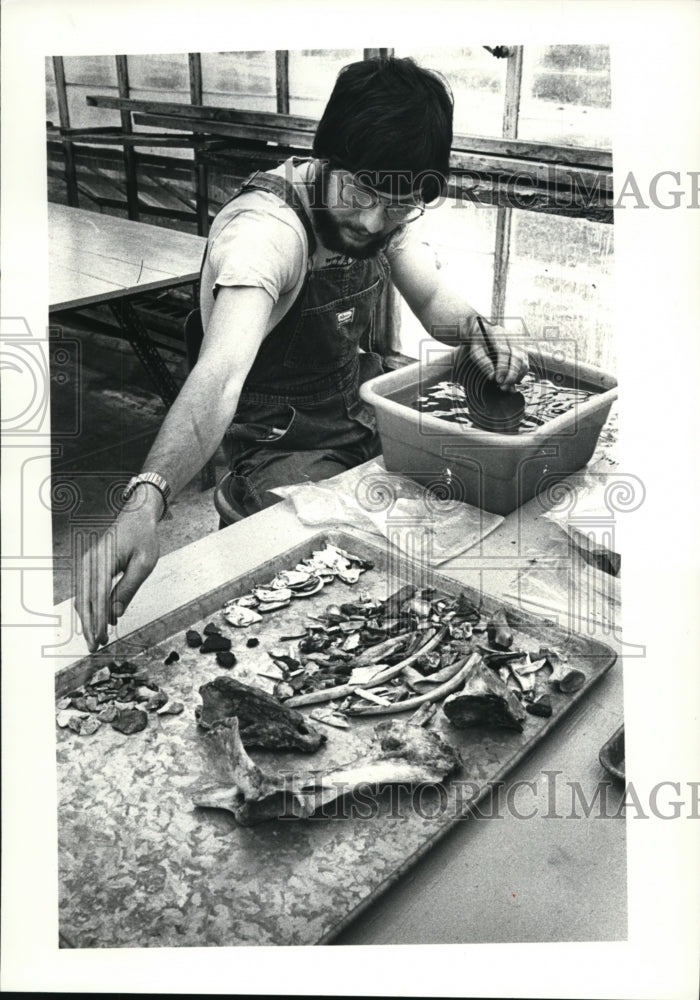 1981 Press Photo Craig Lass washes pieces of bone and rock found by students - Historic Images
