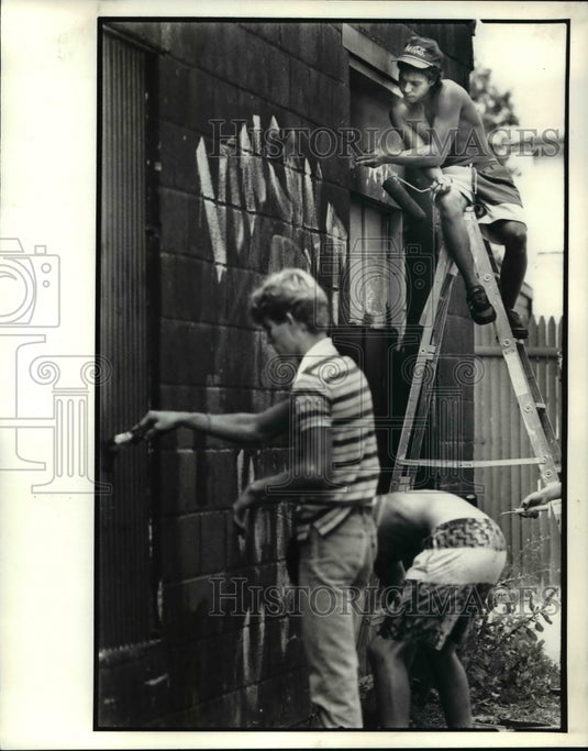 1988 Press Photo Nelson Gonzales Scraps Off Paint as Kids Paint over Graffiti - Historic Images