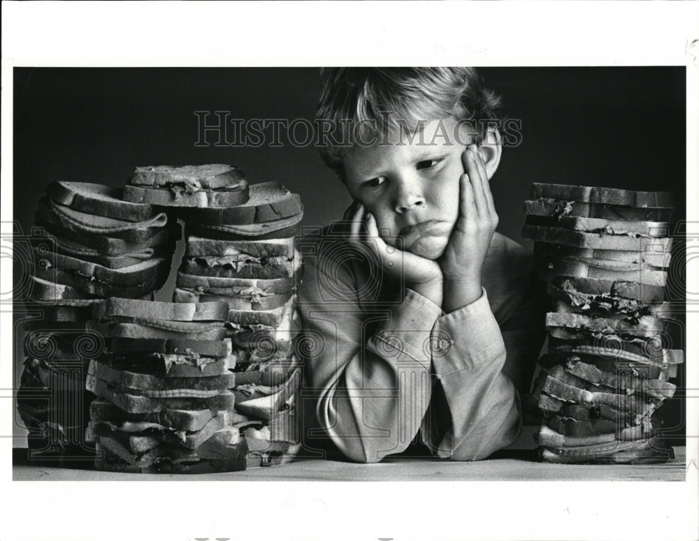 1986 Press Photo Mat Duncan looks at peanut butter and jelly sandwiches - Historic Images