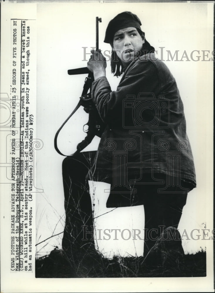 1973 Press Photo Indian Youth in Jeans and a beret Kneels on a hill - Historic Images
