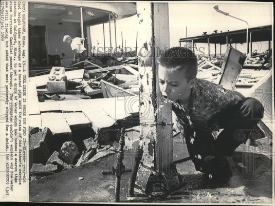 1969 Press Photo Carl Wright takes advantage of a busted pipe amid the ruins - Historic Images