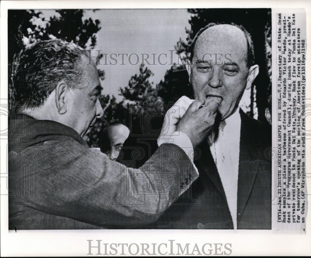 1962 Press Photo Dean Rusk Samples A Barbecue Offered By Eduardo Victor Haedo - Historic Images