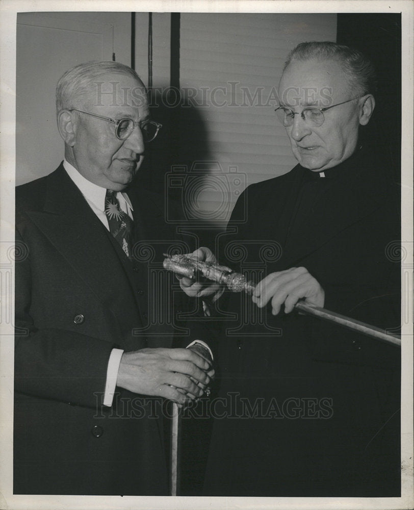 Men examine cane priest-Historic Images