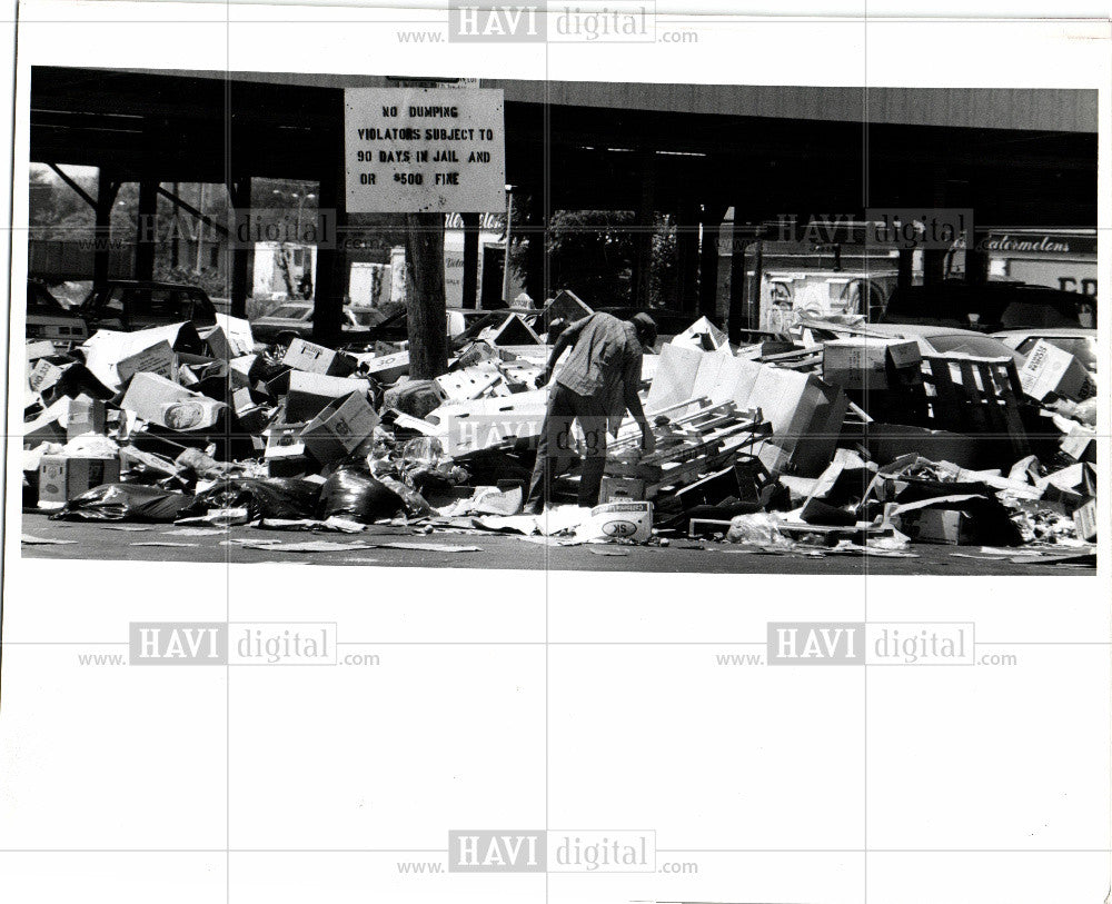 Press Photo Man paws through trash pile at market - Historic Images