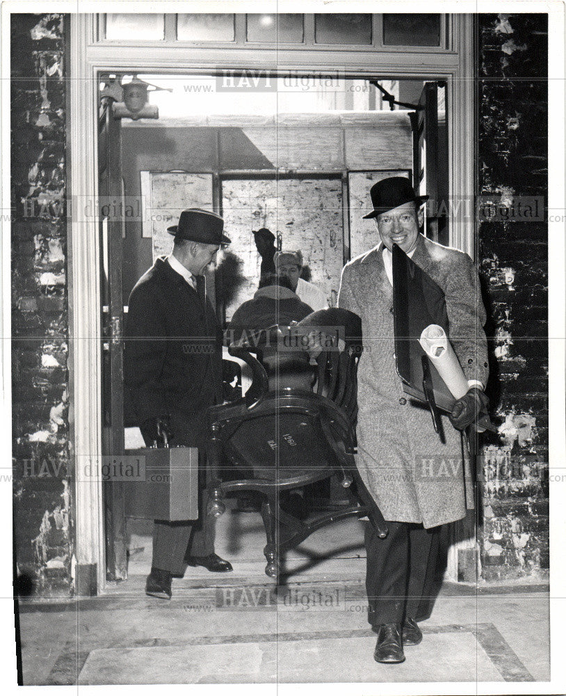 Press Photo Man carring chair out of building - Historic Images