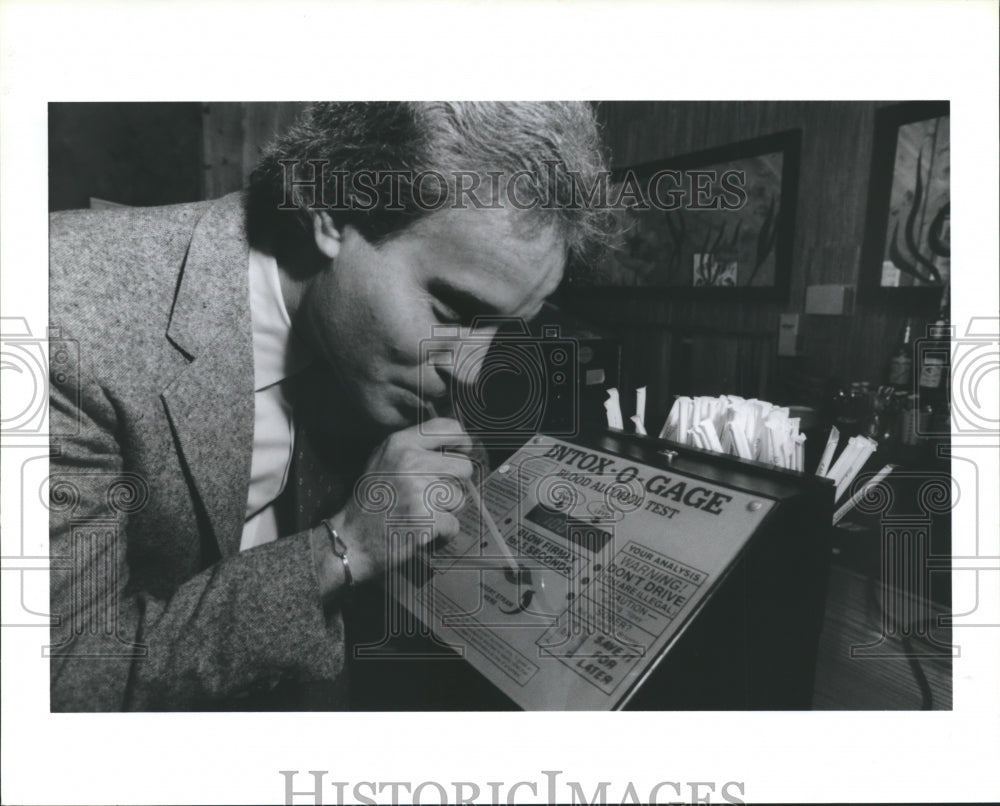 1986 Press Photo Alex Vandix Blows in Breathalyzer Machine Drusilla's Restaurant - Historic Images