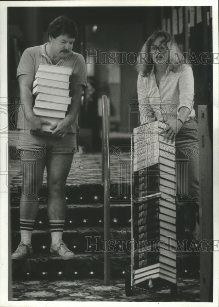 1984 Press Photo Couple moving a stack of books at Bookstop in Houston bookstore - Historic Images