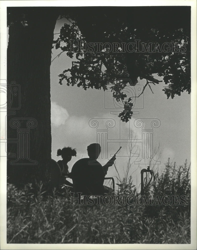 1984 Press Photo Father and daughter hunt from under a tree in Clay, Texas - Historic Images