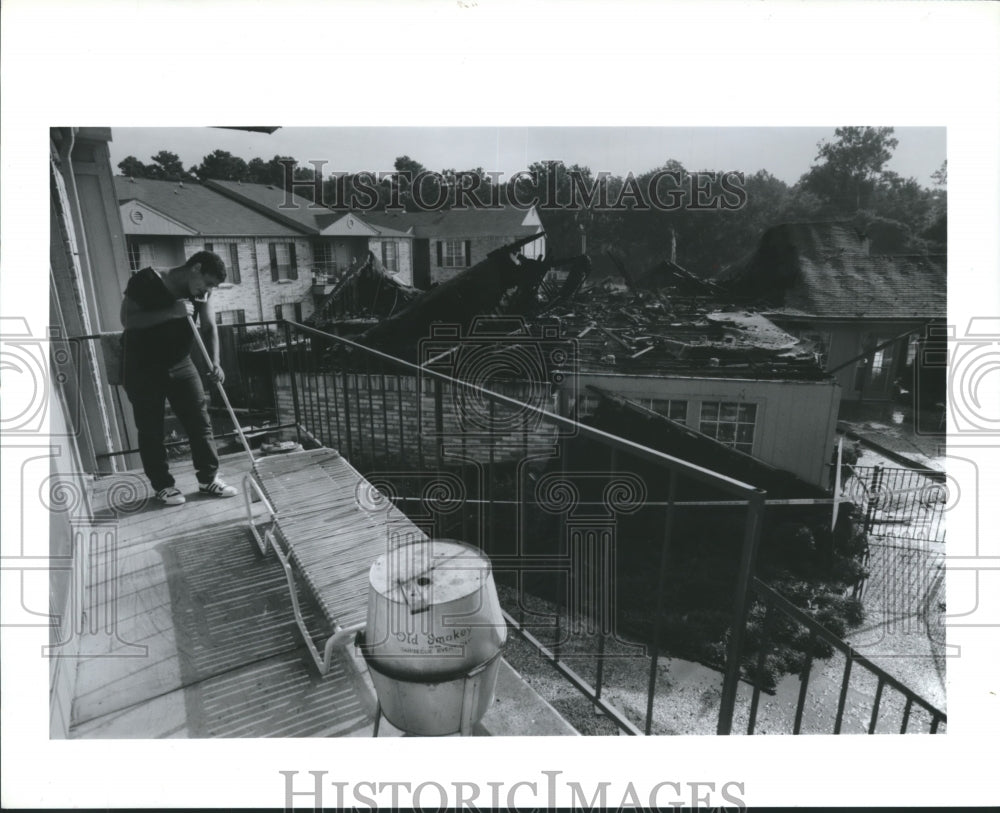 1989 Press Photo Mark Stovall sweeps balcony at Cornerstone Apartments, Houston - Historic Images