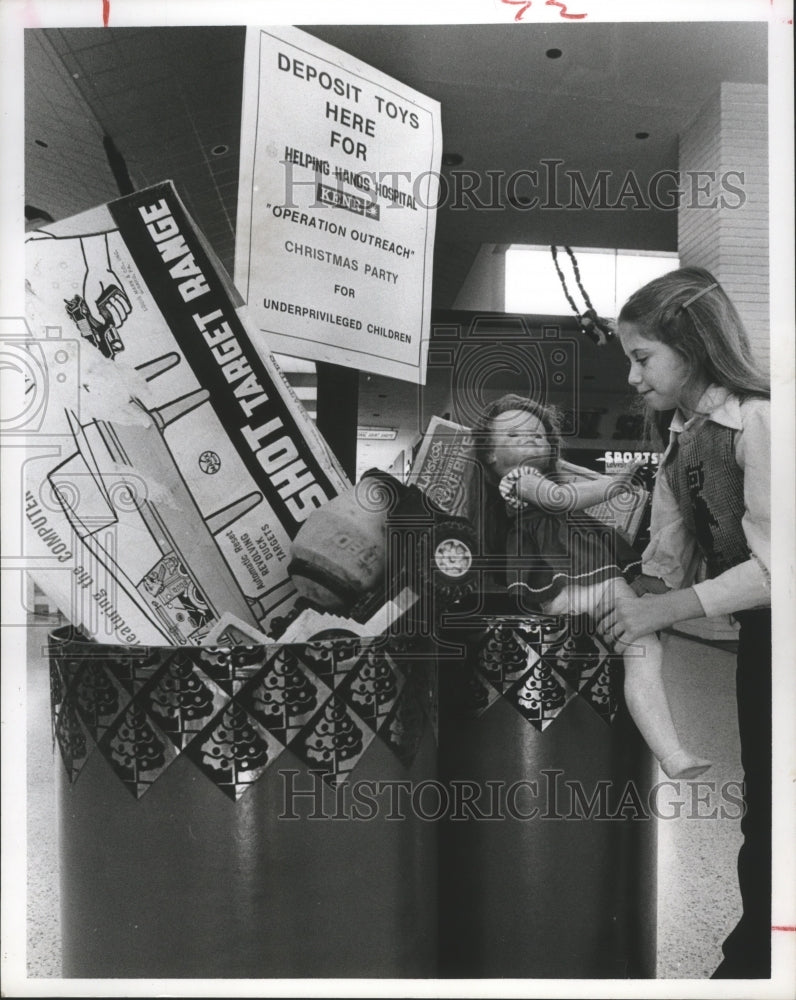 1977 Holly Chapa donates a doll for Helping Hands Christmas, Houston - Historic Images