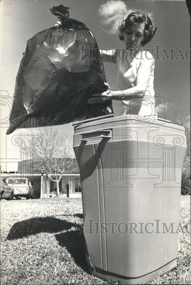 1976 Lady dumps her garbage in a garbage can - Historic Images