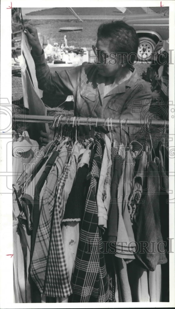 1987 Press Photo Lupe Mead goes through clothes rack at Houston garage sale - Historic Images