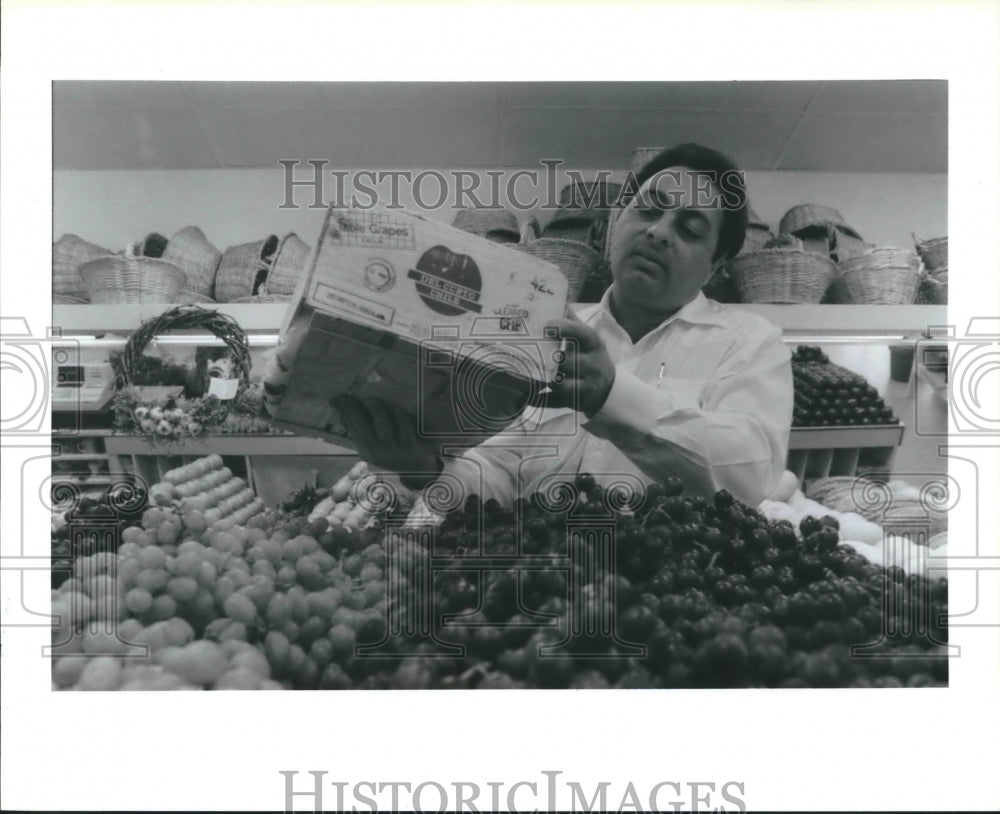 1989 Worker displays fruit in his store - Historic Images