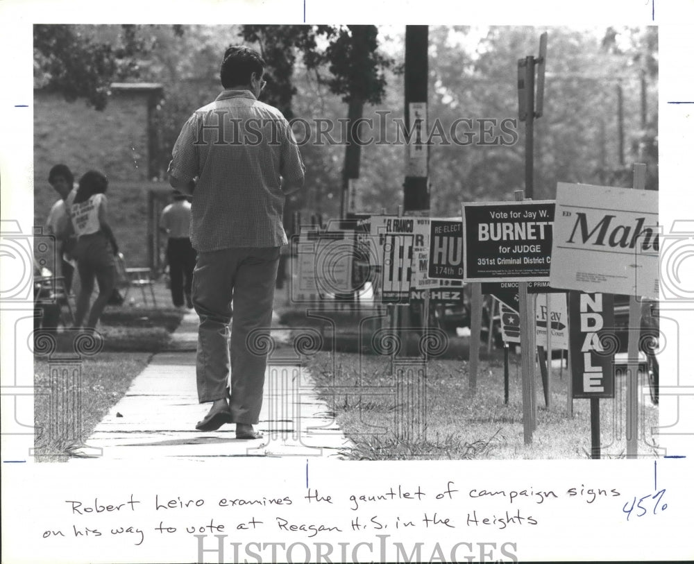 1984 Robert Leiro examines campaign signs in Houston, TX - Historic Images