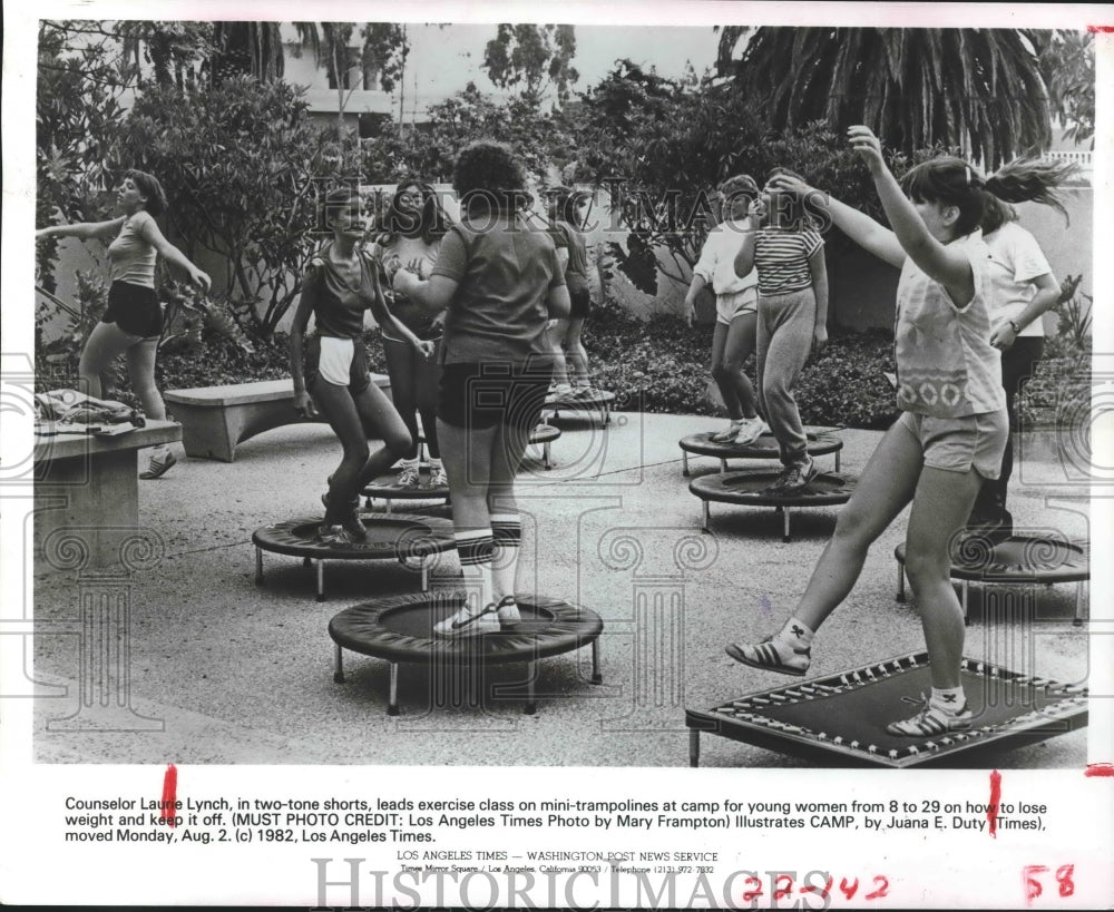 1982 Counselor Laurie Lynch leads exercise class on trampolines - Historic Images