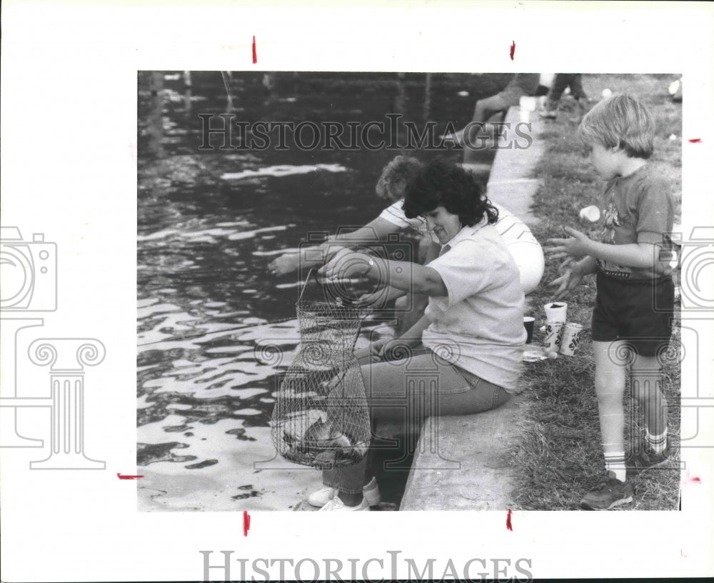 1988 Press Photo Woman holds a wire fish basket to display their catch in Texas - Historic Images