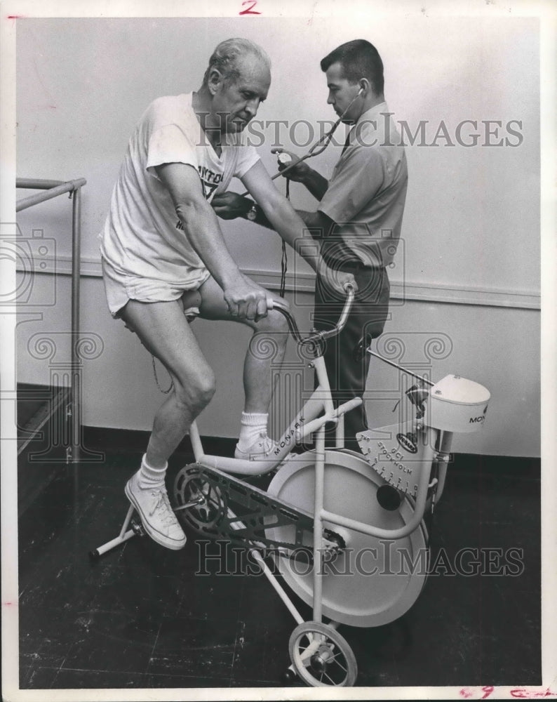 1971 Press Photo J. T. Nesbitt on exercise bike with tester Al Johnston - Historic Images