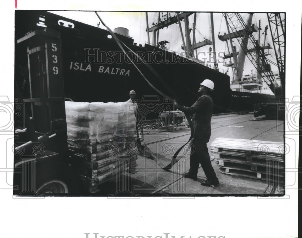1990 Men load Isla Baltra of Ecuador with material from Baroid Co - Historic Images