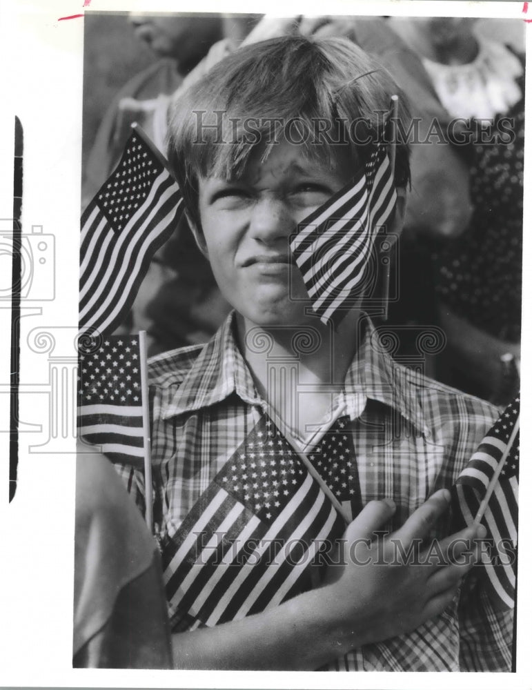 1990 Surrounded by small flags, Jason Anderson salutes American flag - Historic Images