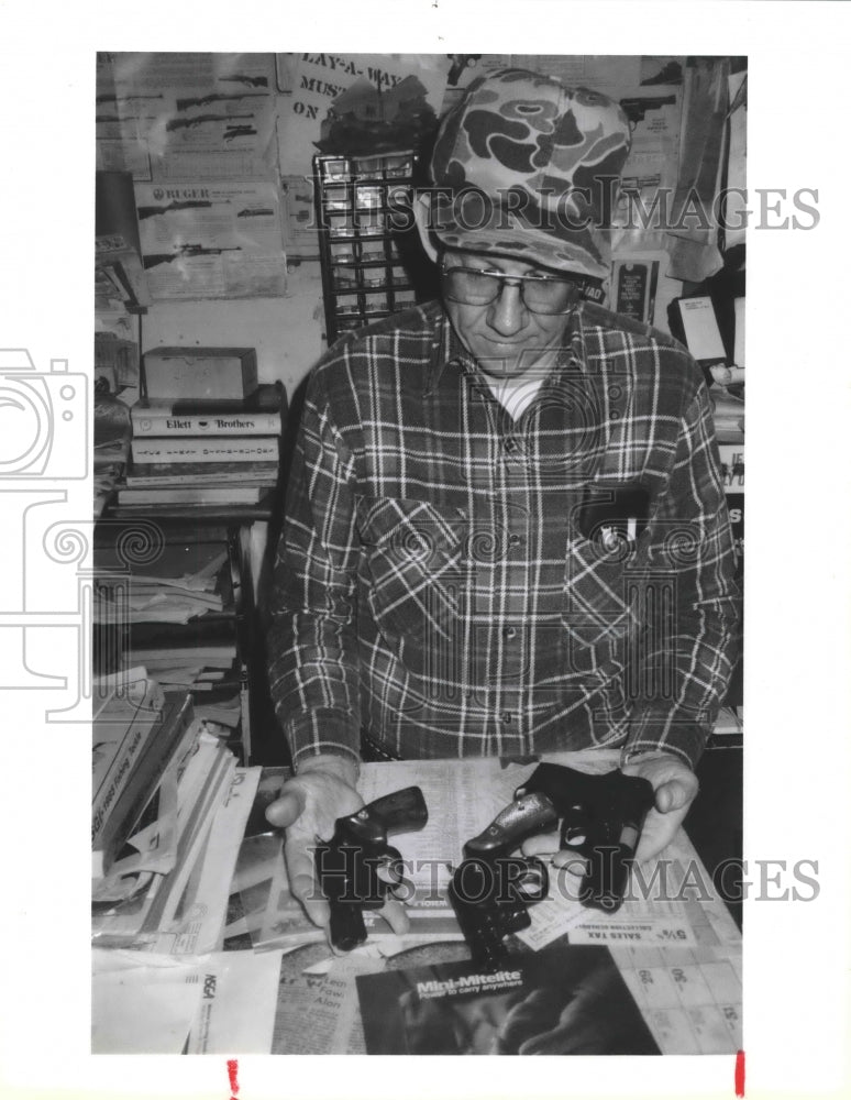 1985 Ben Pavlic, owner of Ben's Gun Ship displays handguns - Historic Images