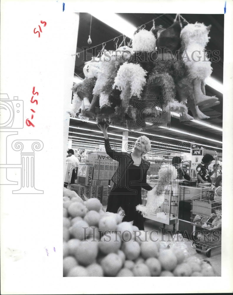 1983 Beverley Sutton looks at pinatas at Fiesta Mart in Houston - Historic Images
