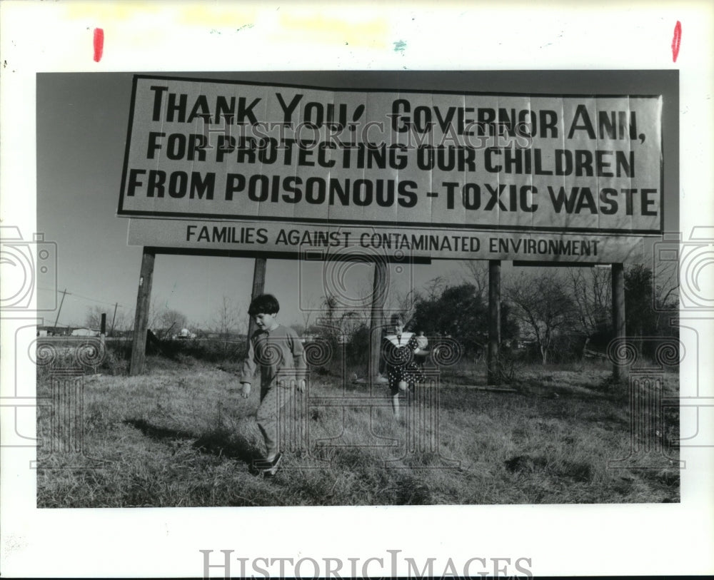 1991 Children play under anti-toxic waste sign in Dayton, TX - Historic Images