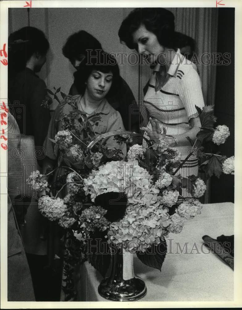 1979 Woman examine flower arrangement in silver art nouveau basket - Historic Images