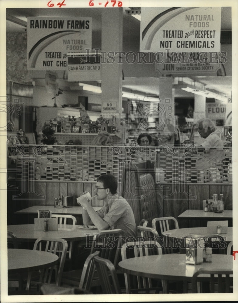 1979 Health food shopper takes break to eat in the store restaurant - Historic Images