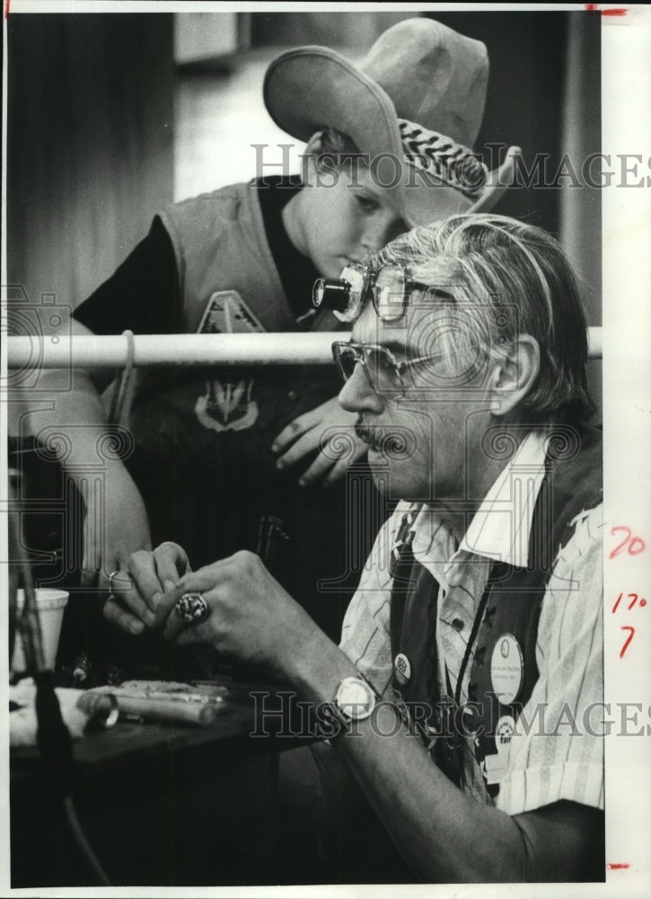 1981 Child watches Maxi Reneau fix jewelry at Harris Co Fair, TX - Historic Images