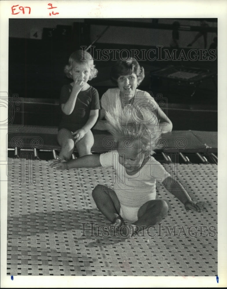 1980 Baby Abigail Janes jumps on trampoline in Texas as others watch - Historic Images