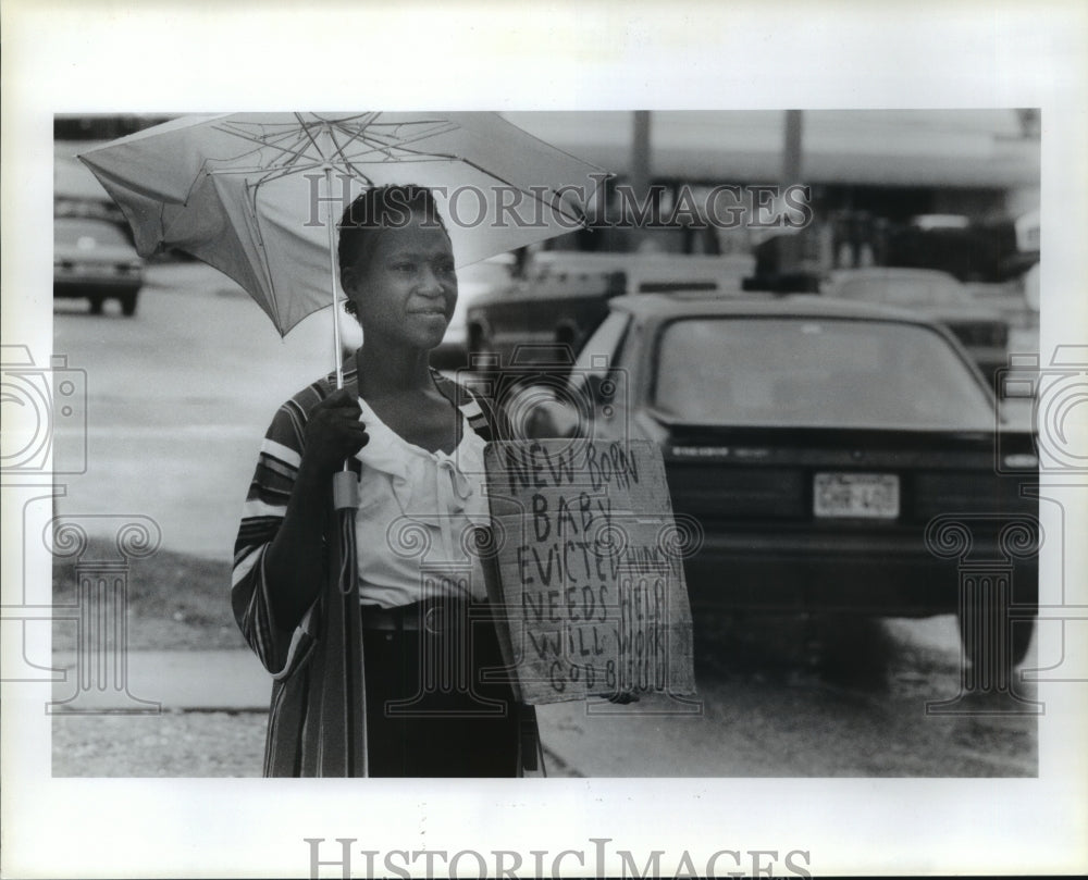 1993 Houston homeless woman holds sign on street corner in rain - Historic Images
