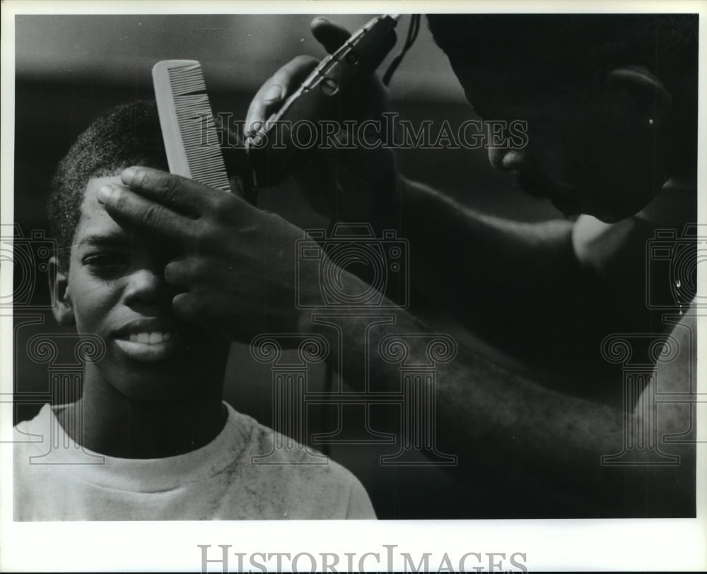 1990 Volunteer gives homeless boy a haircut in Houston at event - Historic Images