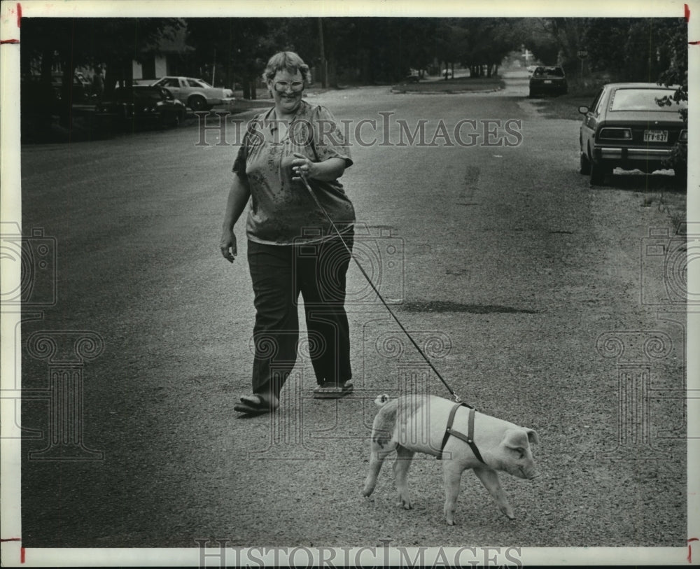 1984 Woman walks pig on leash down Texas street - Historic Images