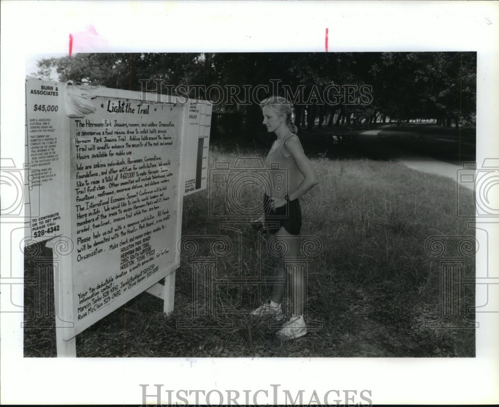 1991 Alisa Wright-Colopy reads sign at Hermann Park, Houston, Texas - Historic Images