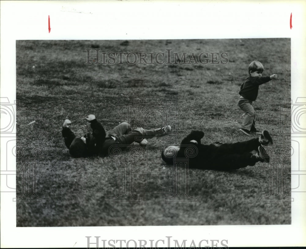 1987 Children roll down hill in Hermann Park, Houston, Texas - Historic Images