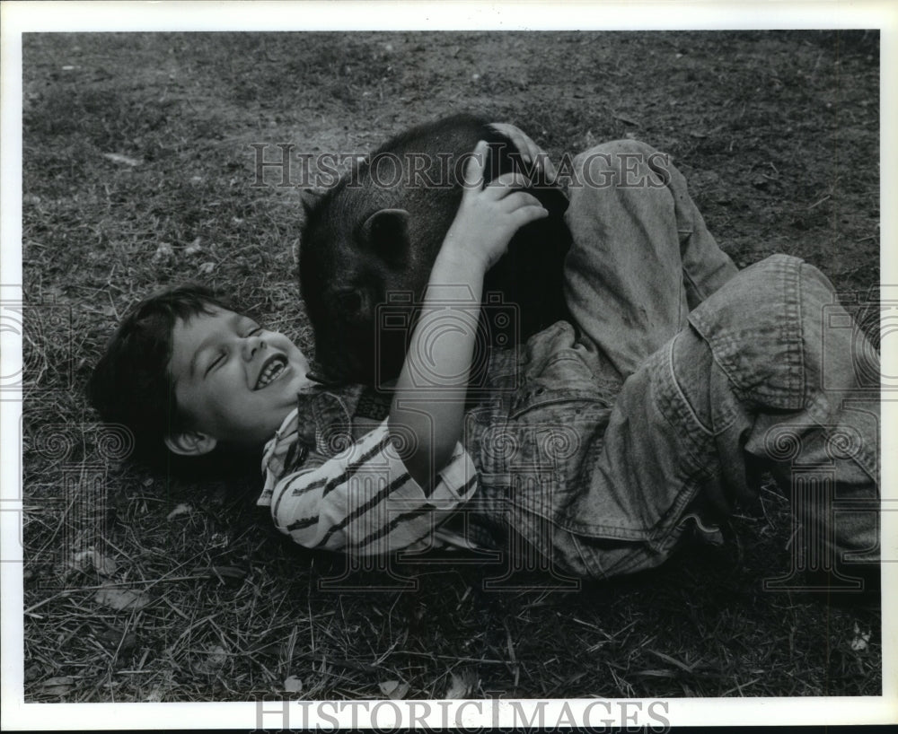 1992 Paul Kilgore plays with potbellied pig in Baytown yard - Historic Images