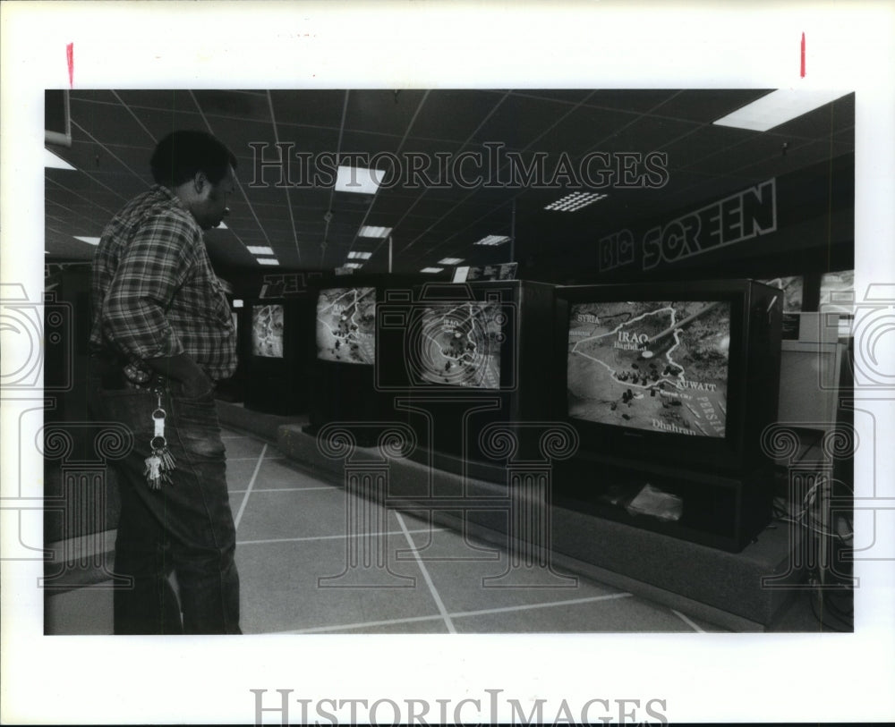 1991 Customer watches news on TV at Highland Superstore in Houston - Historic Images