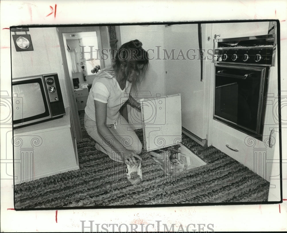 1979 Woman stores food in cupboard in houseboat floor - Historic Images
