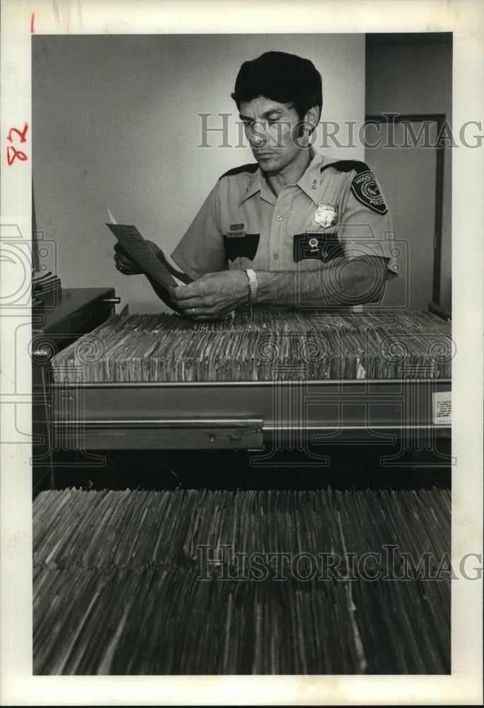 1983 Houston Police Officer Fred Braune checks hit-and-run report - Historic Images