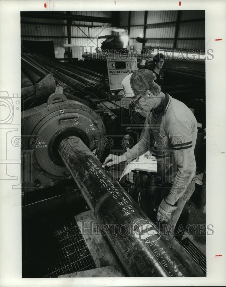 1984 Hoesch Tubular Products worker stencils pipe in Houston - Historic Images