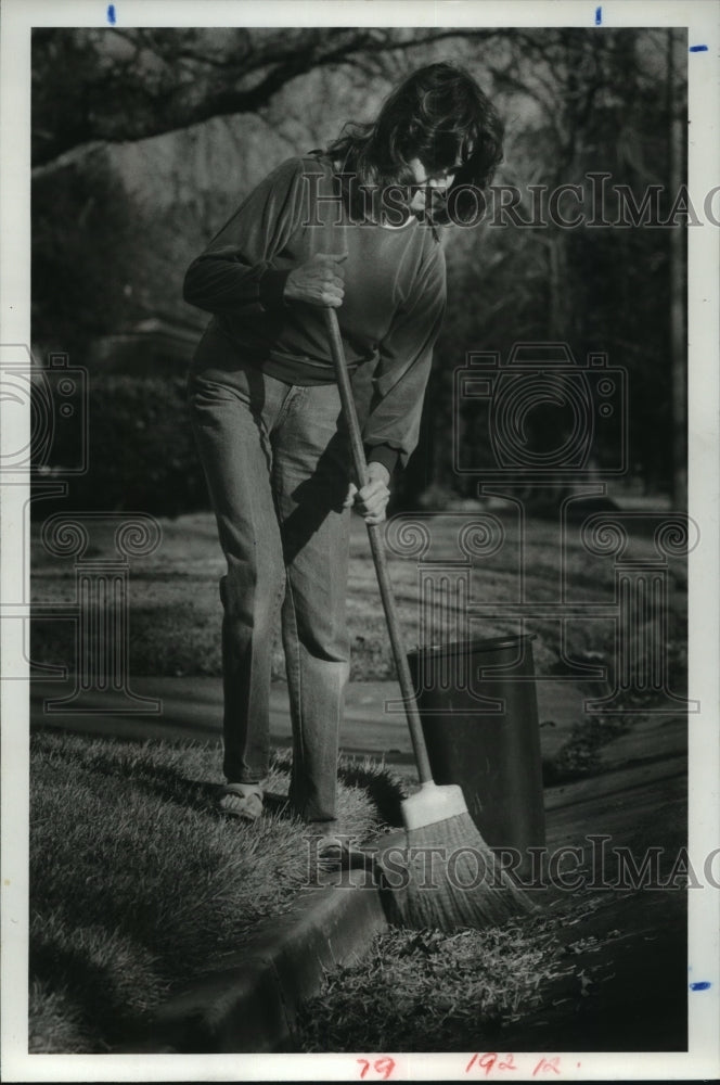 1983 Carol Fogleman sweeps leaves on street in W Univ, Houston, TX - Historic Images