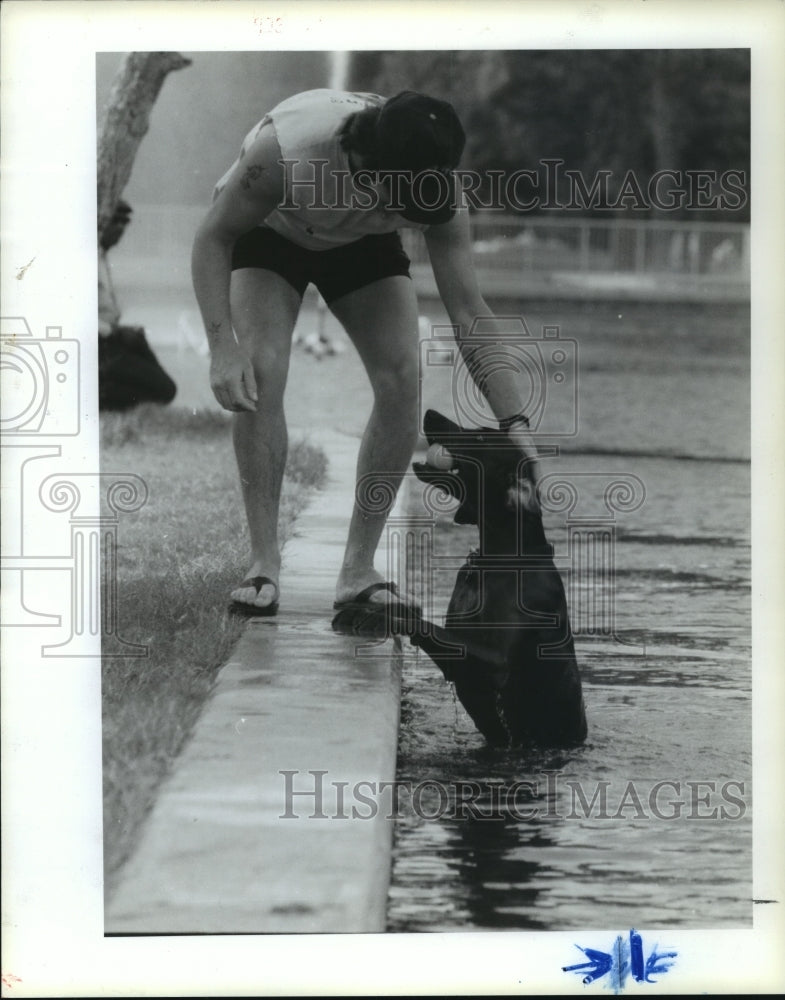 1988 Alan Chiasson plays ball with dog in Hermann Park water in TX - Historic Images