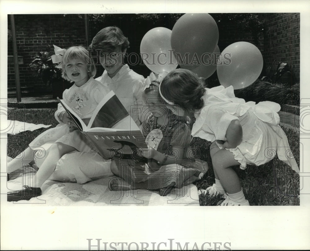1985 Children read Fantasia book on lawn, Houston Symphony - Historic Images