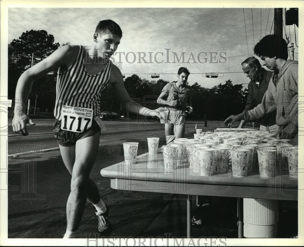1979 Houston Marathon runners grab water from volunteers - Historic Images